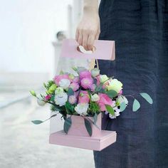 a person holding a pink box with flowers in it