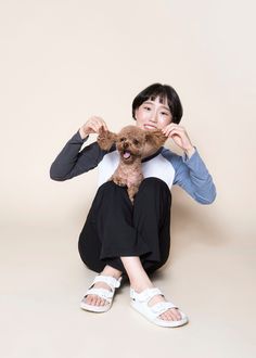 a woman holding a teddy bear in front of her face while sitting on the floor