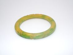 Up for your consideration is this Vintage Bakelite Bangle. This end of day bakelite bangle is quite gorgeous; with yellow and green marbleization and heavily carved details that wraps around the outside of the piece. Pictures best describe. Excellent condition, no dents or damages.  Measurement is Approx.: 8 inches around the inside Width of Bangle is Approx.: 3/8 inch wide I tested this piece with simichrome and it is guaranteed to be bakelite. E-mail me with any questions you may have prior to Green Carved Round Bangle, Carved Green Jade Bangle, Green Carved Bangle Bracelet, Green Carved Bangle Bracelets, Vintage Adjustable Green Bangle, Adjustable Green Vintage Bangle, Vintage Green Adjustable Bangle, Retro Green Bangle Bracelets, Bakelite Bangles