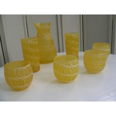 yellow glass vases and bowls sitting on a white tableclothed surface, with one in the center