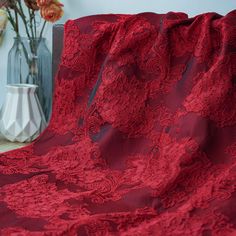 the red lace is on top of the table next to a vase with flowers in it