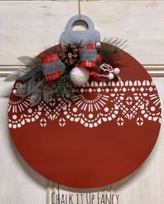 a red and white christmas ornament hanging on a door with pineconi