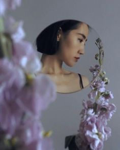 a woman holding flowers in front of her face and looking at the camera with an instagram