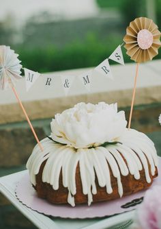 a bundt cake with icing and decorations on top sitting on a table outside