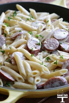 a pan filled with pasta and sausage on top of a table