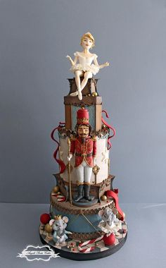 a three tiered cake with figurines on top and decorations around the edges