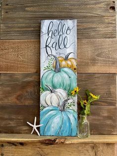 a painted sign that says hello fall with pumpkins and starfish on the shelf