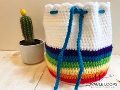 a crocheted bucket bag sitting on top of a table next to a cactus