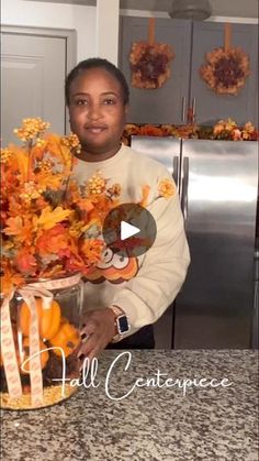 a woman standing in front of a kitchen counter holding a vase filled with orange flowers