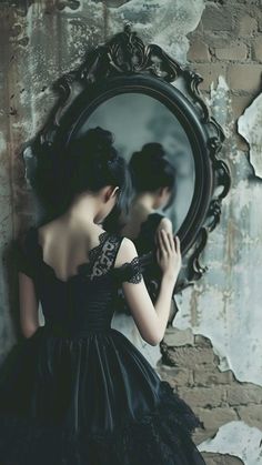 a woman in a black dress looking into a mirror