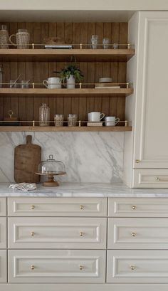 a kitchen with white cabinets and marble counter tops, gold hardware on the upper shelves