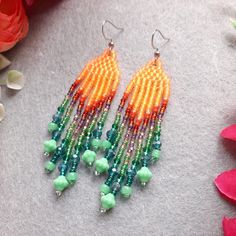 a pair of colorful beaded earrings sitting on top of a table next to flowers