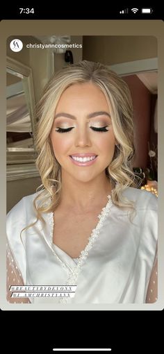 a woman with blonde hair and makeup looks at the camera while wearing a white top