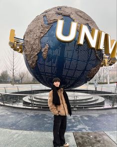 a woman standing in front of a giant globe with the word universal written on it