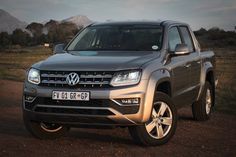 the front end of a silver vw atlas pickup truck parked on a dirt road