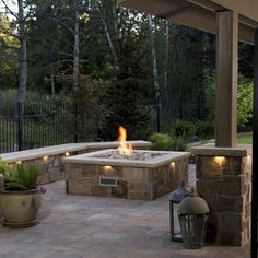 an outdoor fire pit surrounded by potted plants