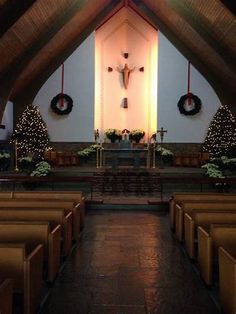 the inside of a church with pews and christmas wreaths on the alter wall