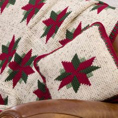 a brown leather chair with a red and green blanket on it's back sitting next to a white brick wall