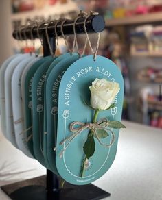 four tags hang on a rack with a white rose