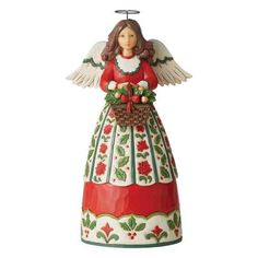 an angel figurine holding a basket with holly wreaths on it's side