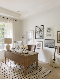 a living room with pictures on the wall and a desk in front of a window