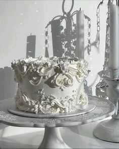 a white cake sitting on top of a table next to a candelabra