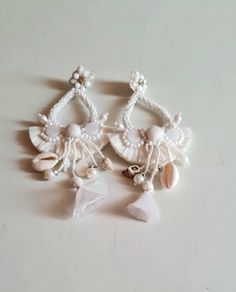 "Bohemian statement all white wedding  statement long earrings. The earrings are purely handmade and handcrafted using raffia, shell, pompoms, glass beads, fabric tassels, and many more elements. These are beautifully put together to get this statement look. The earrings are an ideal wedding or evening formal wear. The earrings measure approx. 5\" long with the charms hanging and 2\" wide. At Carnation jewellery, each piece is handmade and handcrafted in India. There may be a slight imperfection White Clip-on Dangle Bridal Earrings, Handmade White Dangle Clip-on Earrings, White Clip-on Bridal Earrings For Party, Bohemian Drop Clip-on Earrings For Wedding, Handmade Bohemian Bridal Earrings For Party, Handmade Tassel Earrings For Wedding, Handmade Clip-on Earrings For Wedding, Bohemian Tassel Dangle Earrings For Wedding, Handmade Dangle Tassel Earrings For Wedding