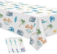 a white table cloth with blue surfboards and palm trees on it, along with two napkins