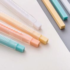 four different colored pens sitting next to each other on a white surface with blue and yellow tips