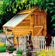 a small wooden shed sitting next to a white picket fence