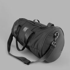 a black duffel bag sitting on top of a gray floor next to a white wall