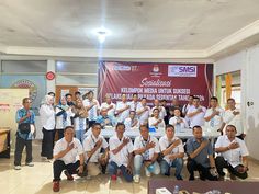 a group of people in white shirts posing for a photo with a banner behind them