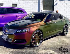 two different colored cars parked in front of a building