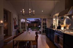 a kitchen and dining room with an open door leading to the back yard at night