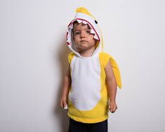 a little boy dressed in a yellow and white costume with a shark on it's back