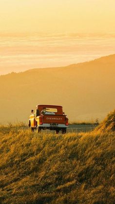 an old truck is parked on the side of a hill with grass in front of it