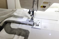 the sewing machine is on top of the white fabric with black and grey designs in it