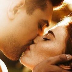 a man and woman kissing each other while the sun shines down on their faces