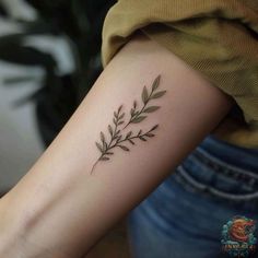 a woman's arm with a small branch tattoo on the left side of her arm