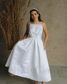 a woman in a white dress standing next to a plant