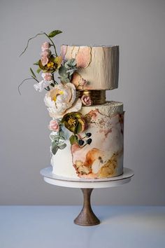 a three tiered cake decorated with flowers and leaves