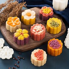 several different types of soaps on a wooden tray next to dried flowers and seeds