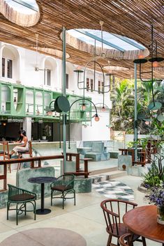 the inside of a restaurant with tables, chairs and potted plants hanging from the ceiling