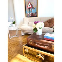 a living room with a couch, coffee table and suitcases on the wooden floor