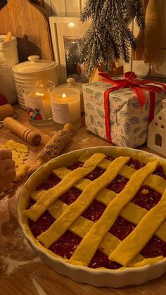 a pie sitting on top of a wooden table next to a christmas tree and candles