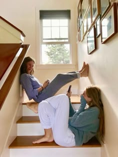 two women are sitting on the stairs and one is holding a cell phone in her hand