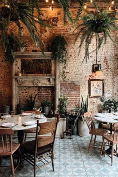 an indoor dining area with brick walls and potted plants hanging from the ceiling, surrounded by wooden chairs