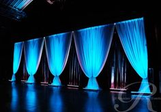 an image of a stage setting with blue lights and drapes on the side wall