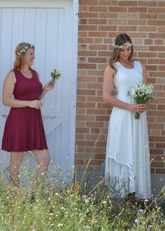 two women standing next to each other in front of a brick wall with flowers on their heads