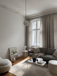 a living room filled with furniture next to a large window covered in curtains and drapes